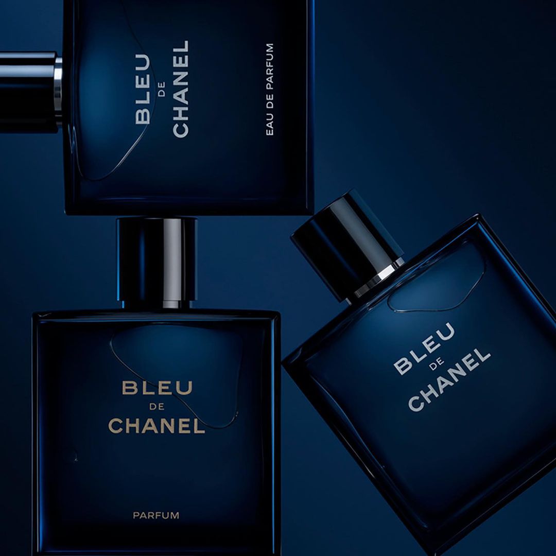 Three Bleu de Chanel perfume bottles arranged on a dark blue background. Square bottles with silver accents and visible product labels.
