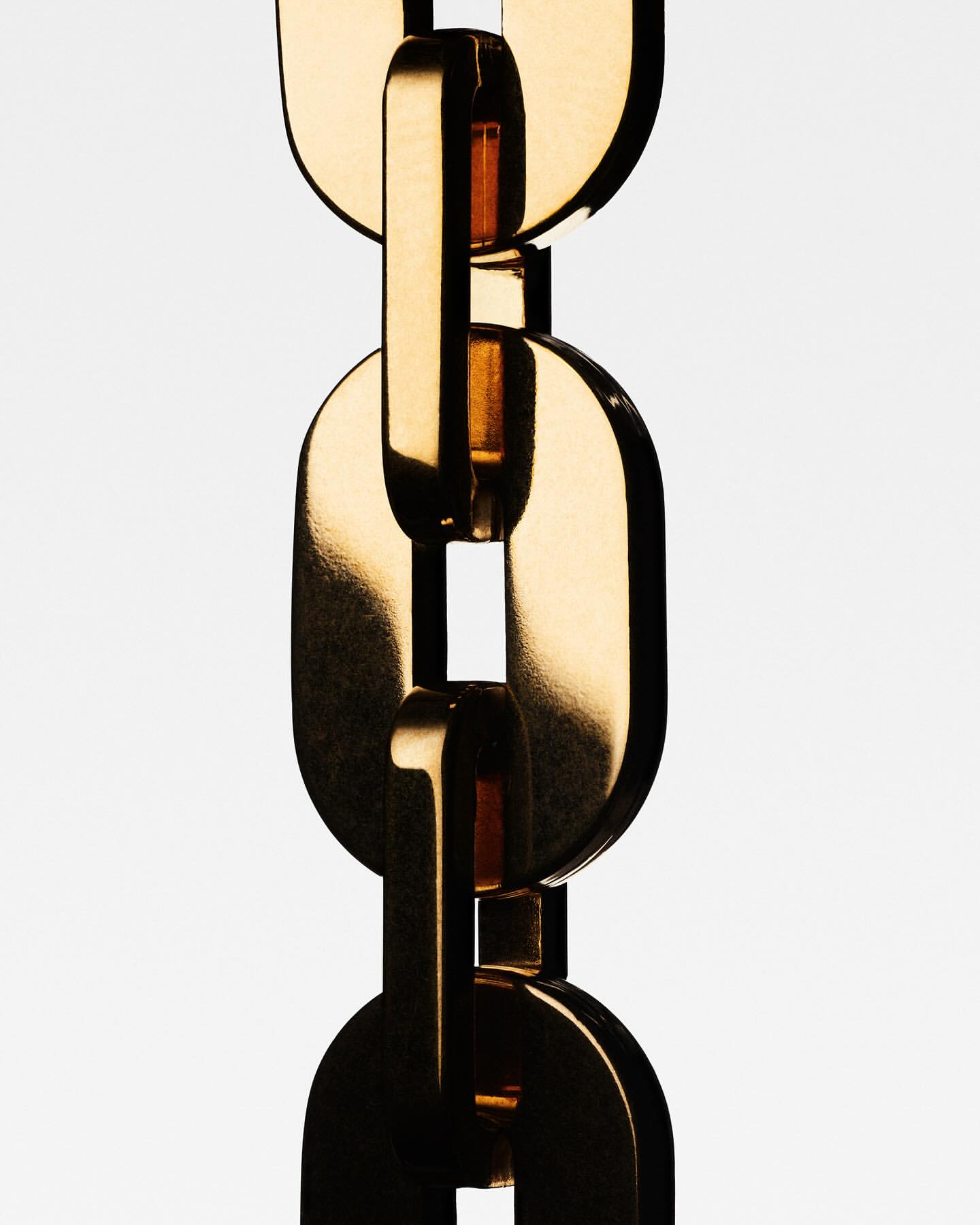 Close-up of gold chain links against a white background, showcasing the metallic texture and interlocking design of the jewelry.