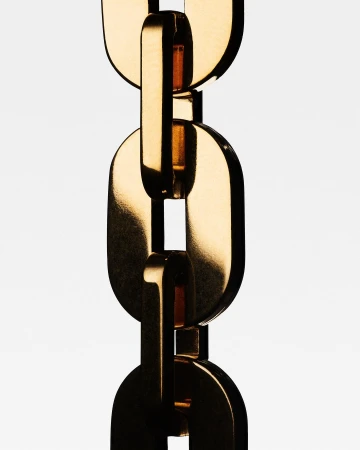 Close-up of gold chain links against a white background, showcasing the metallic texture and interlocking design of the jewelry.