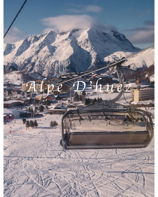 Scenic view of Alpe d'Huez ski resort with snowy mountain peaks, residential buildings, and ski tracks under a clear blue sky.