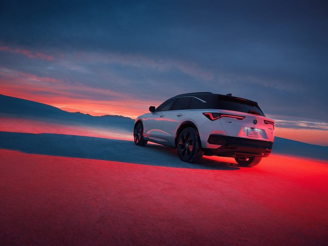 Acura SUV parked on a white, flat landscape with a sunset in the background, showcasing its modern design and rugged capabilities.