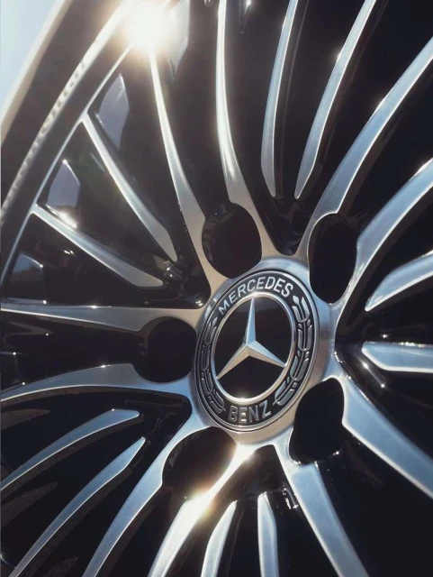 Close-up of a Mercedes-Benz wheel rim featuring a silver multi-spoke design and the Mercedes-Benz logo at the center.