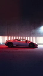 Side profile of a luxury sports car parked against a concrete wall lit by a horizontal strip of warm red lights.