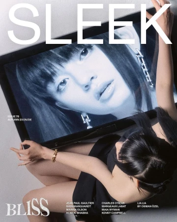Magazine cover featuring a model reflected in a television screen. The model in the photo is wearing a black dress and a gold bracelet.