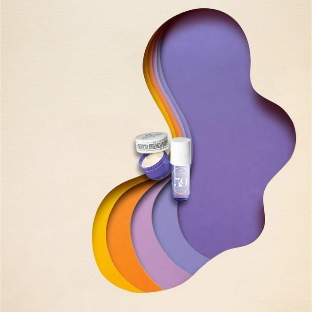 Beauty products including a jar and a bottle, are arranged against a background of layered colorful paper cutouts in purple and yellow tones.