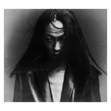 Portrait of a woman with long dark hair blowing across her face wearing a dark jacket photographed by P.a Hue De Fontenay