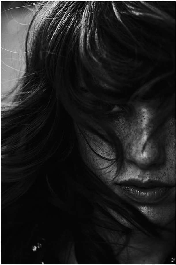 Close-up monochrome portrait of a woman with dark hair covering her eyes and prominent freckles on her nose.