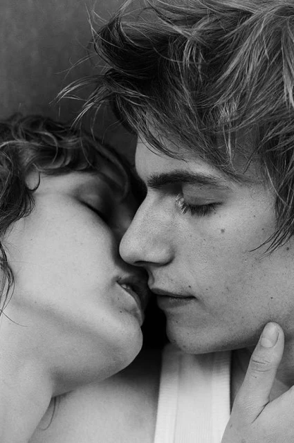Monochrome close-up of an intimate moment between a young adult male and female, lips touching, capturing a tender and romantic scene.