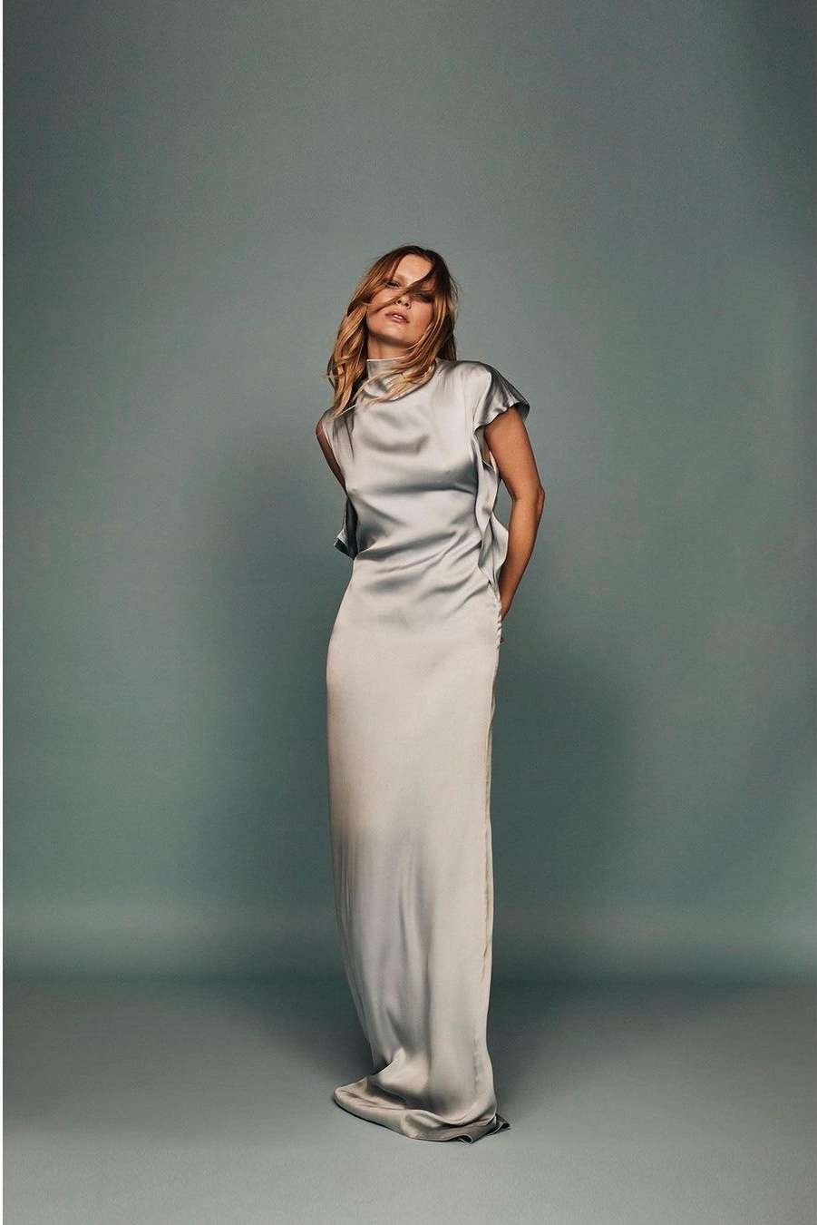 Woman in a long grey satin dress standing against a neutral studio backdrop captured by P.a Hue De Fontenay