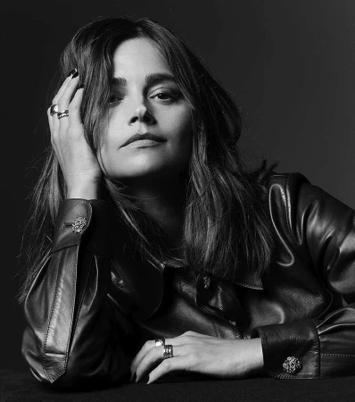 Portrait of a woman wearing a dark leather shirt with her hand raised to her head, shot in monochrome by P.a Hue De Fontenay.