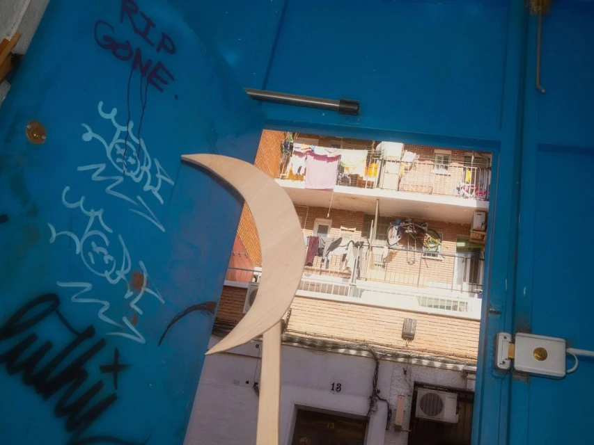 Doorway view of inner courtyard through crescent shape cutout with tag covered door.