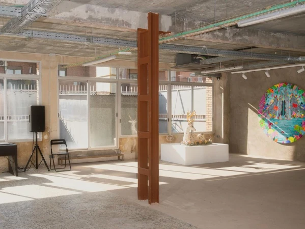 Bright, airy gallery space features an abstract art installation with modern art, speaker, chair, and natural light from large windows.