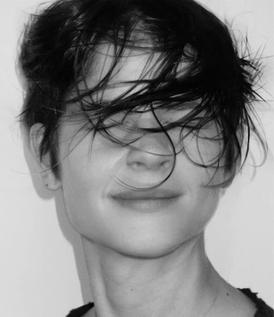Close-up monochrome portrait of a person with dark wet hair covering their eyes against a plain white background.