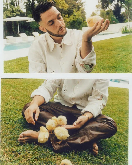 Eye-level shot of a man seated outdoors, interacting with small yellow chicks. One chick sits on his open palm in the sunny scene.