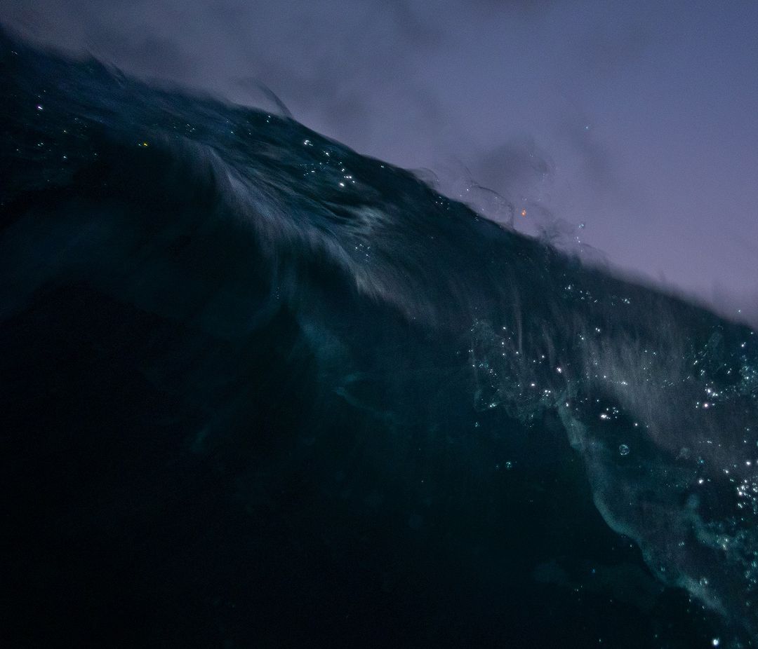 Abstract ocean wave cresting, showcasing the interplay of deep blues, teals, and white highlights in a dynamic seascape composition.