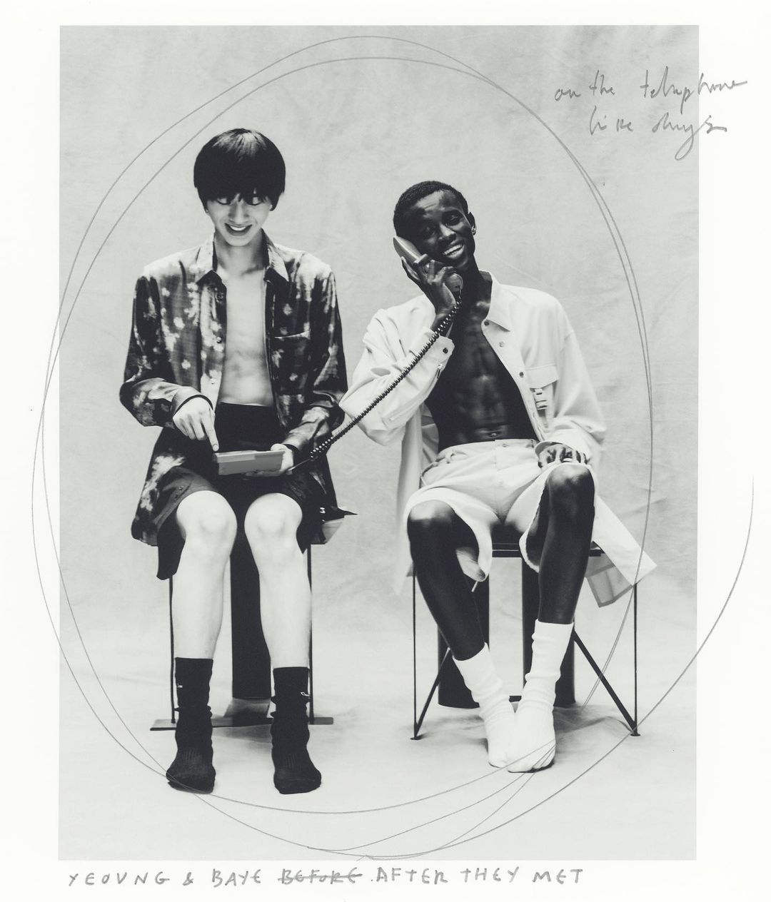 Black and white photo of two young adults seated indoors, one using a telephone while the other interacts with a handheld device.