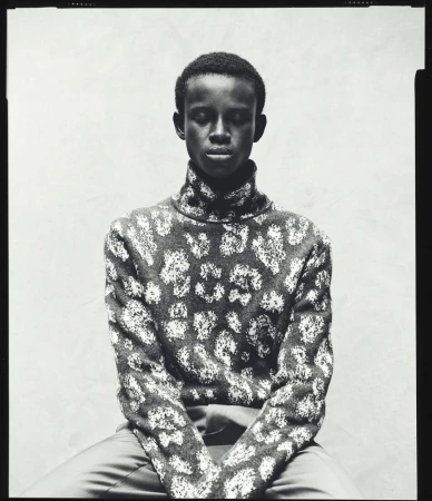 Portrait of a Black man with short hair wearing a patterned turtleneck sweater, photographed in black and white by Pablo Di Prima.