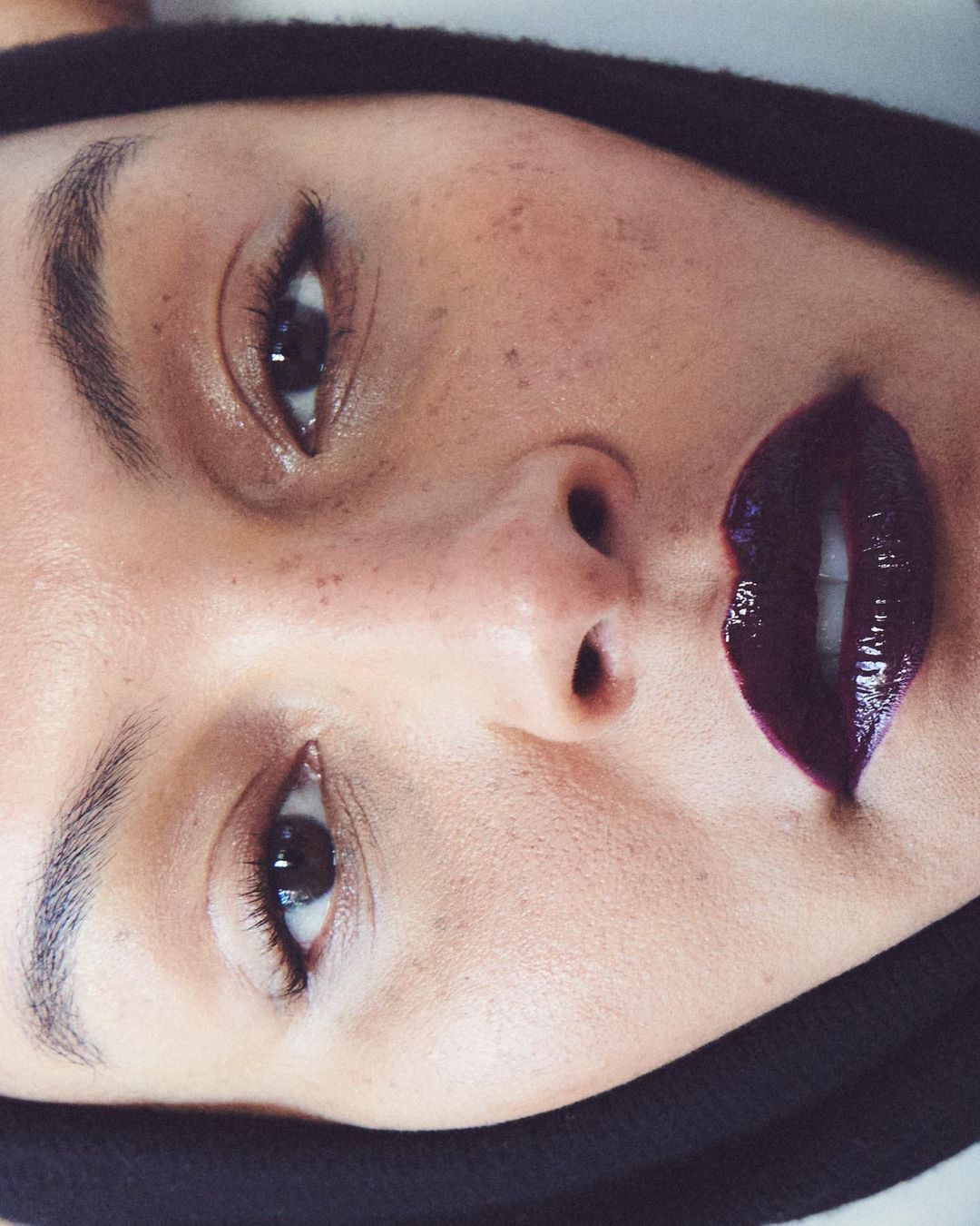 Close-up of a woman with dark lipstick, fair skin and freckles. The image showcases beauty with a close-up shot.