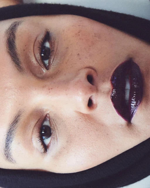Close-up of a woman with dark lipstick, fair skin and freckles. The image showcases beauty with a close-up shot.