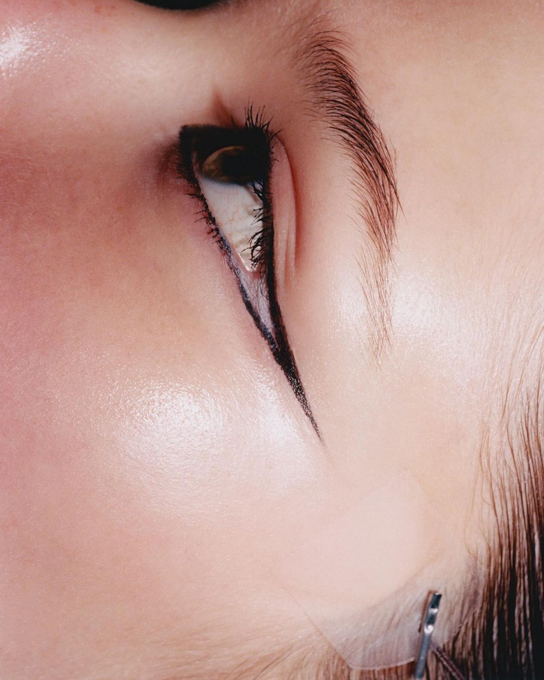 Extreme close-up of adult female eye with dramatic black eyeliner. Beauty shot highlights cosmetic makeup and fair skin.