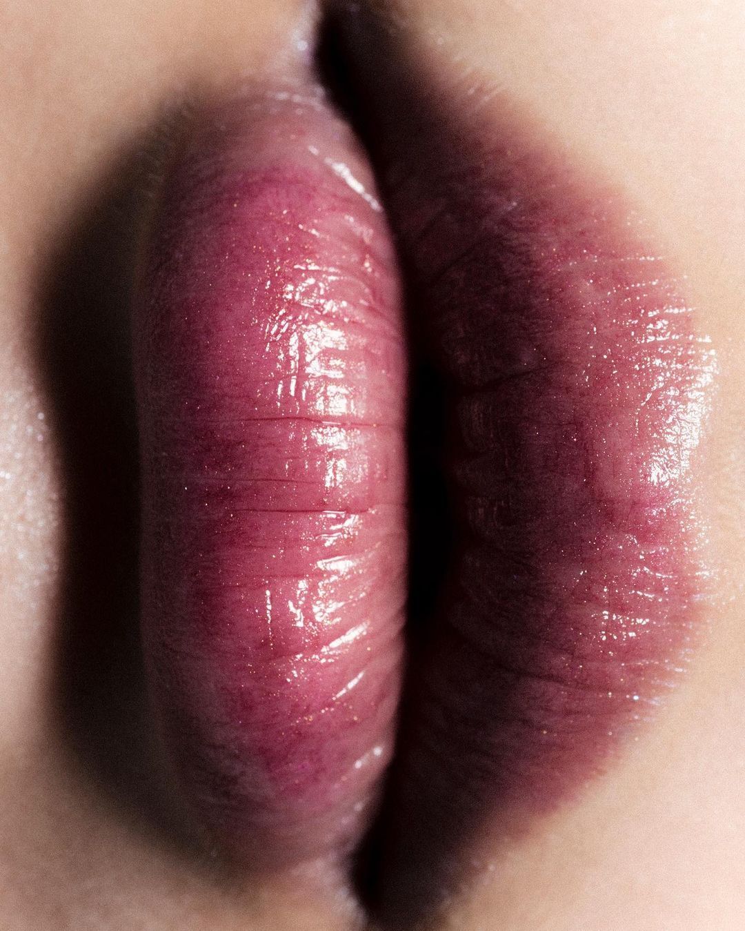 Close-up of an adult female's lips, showcasing their texture, color, and shape, set against a fair skin tone background in a macro photography style.