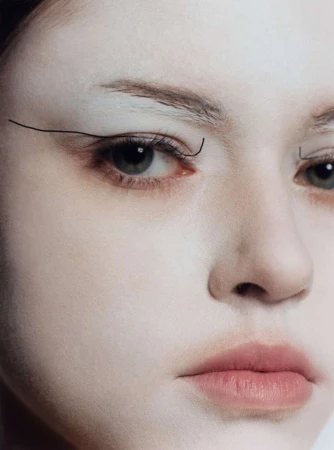 Close-up portrait of a woman with avant-garde makeup and thin graphic eyeliner strokes above her eyes.