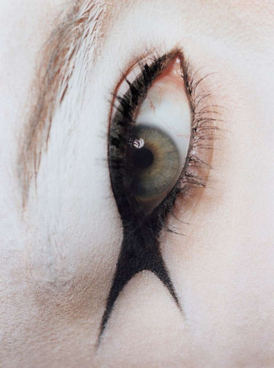 Close-up shot of a human eye with dramatic black makeup extending down the face, creating a striking and artistic look.