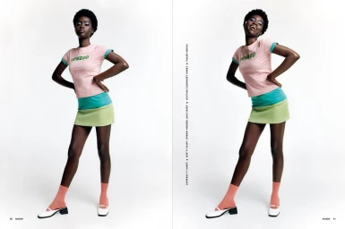 Black woman wearing pink t-shirt, green skirt, orange socks, and white shoes against a white studio background