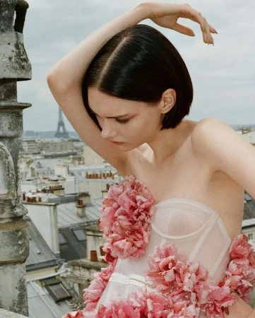 Woman with short dark hair in strapless floral dress posing on Parisian rooftop with Eiffel Tower in background by Pablo Sáez