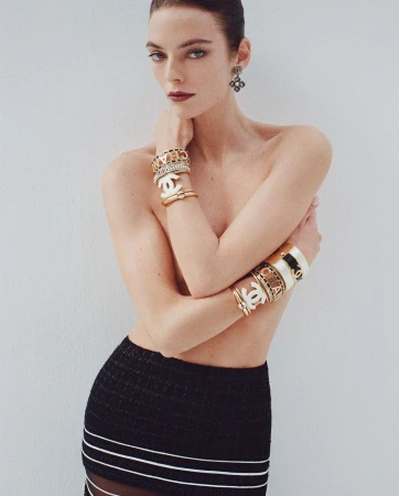 Model wearing stacked designer bracelets and earrings with a black skirt against a white studio background in Paris by Pablo Saez