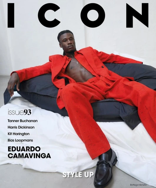 Magazine cover featuring a man in a red suit lounging on cushions, with the magazine's name "ICON" and other text elements displayed.