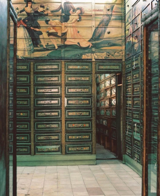 Hallway view of a storage room with wooden drawers, decorated with an antique illustration and filled with boxes, creating depth.