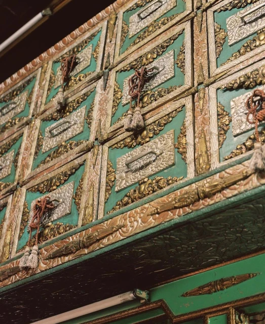 Ornate green and gold wall paneling with decorative trim and tassels, adding an element of vintage charm to interior architecture.