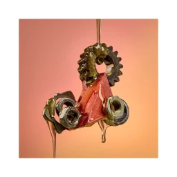 Close-up of metallic gears, nuts, and a red triangular object suspended as golden honey drips down over them