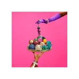 Two hands holding a golden tray piled with colorful decorative ornaments against a vibrant pink background.