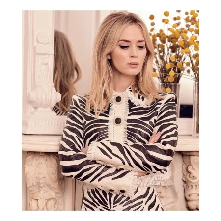 Close-up of woman in zebra-striped jacket standing indoors. The image showcases her outfit, makeup, and styled blonde hair.