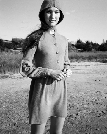 Black and white portrait of a woman wearing a hooded dress standing outdoors on a sandy beach by Pamela Hanson