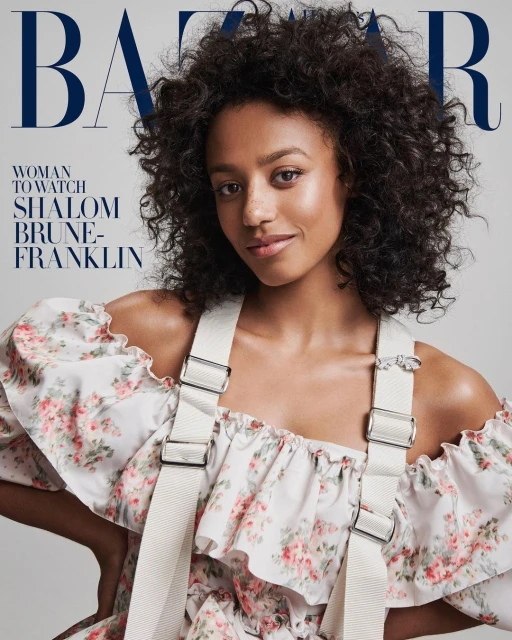 Fashion magazine cover featuring Shalom Brune-Franklin, dark curly hair, wearing floral-patterned dress with white suspender straps, smiling.