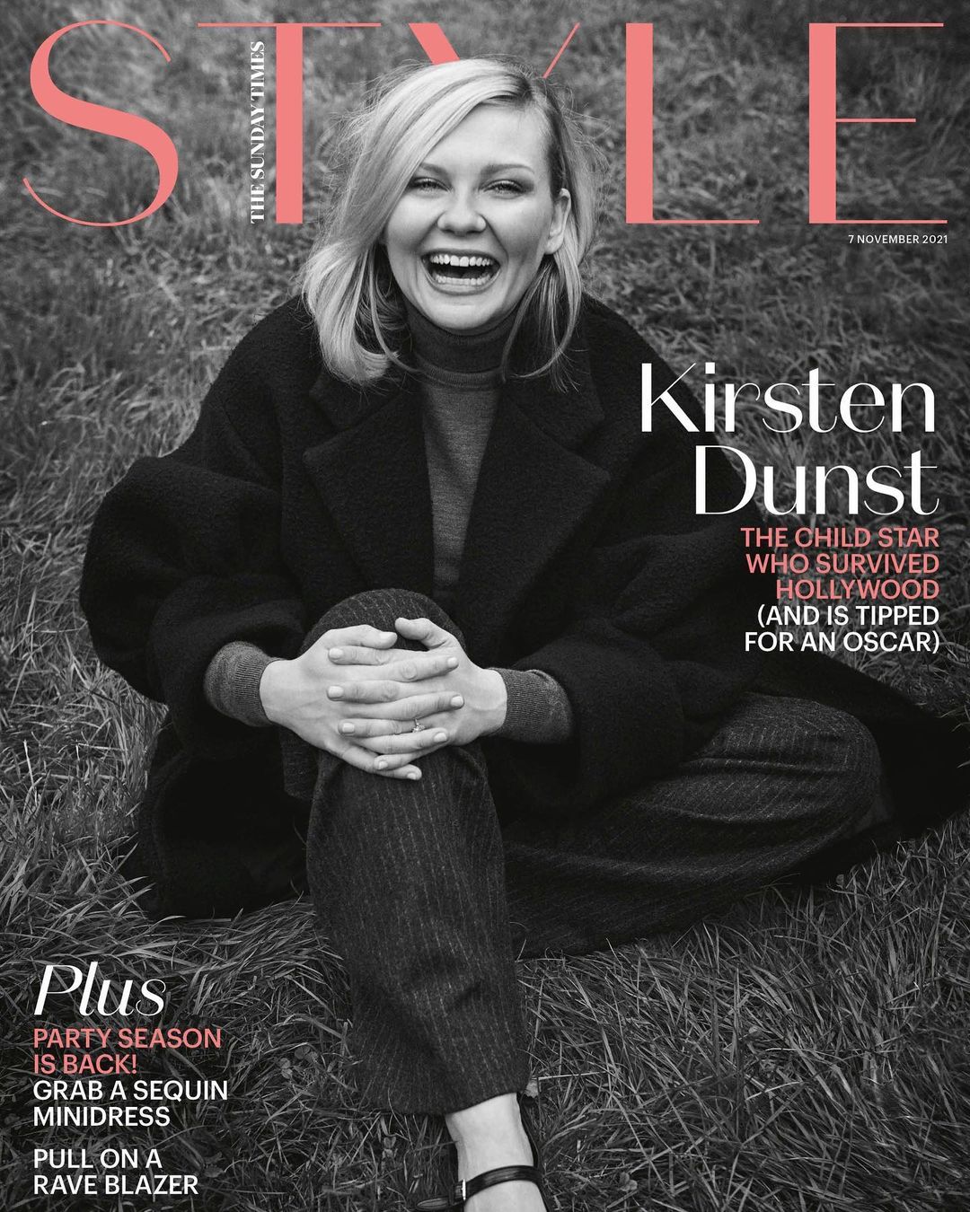 Magazine cover featuring Kirsten Dunst sitting in a field wearing a black coat, grey sweater and patterned pants, laughing, with the title 'Style'.
