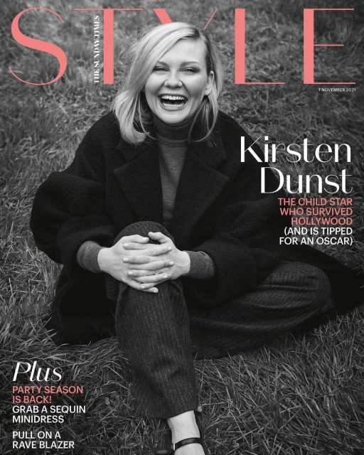 Magazine cover featuring Kirsten Dunst sitting in a field wearing a black coat, grey sweater and patterned pants, laughing, with the title 'Style'.