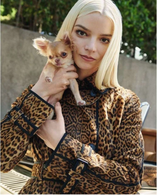 Anya Taylor-Joy poses with a small chihuahua, wearing a leopard-print coat in an outdoor setting, showcasing fashion and celebrity style.