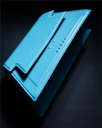 Bright blue leather handbag resting on a dark surface shot from an elevated angle by Paola Dossi in Paris.