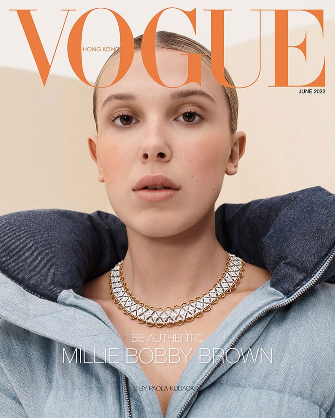 Millie Bobby Brown on Vogue Hong Kong cover, June 2022. Close-up of Brown wearing a denim jacket and gold necklace. Peach-toned background.