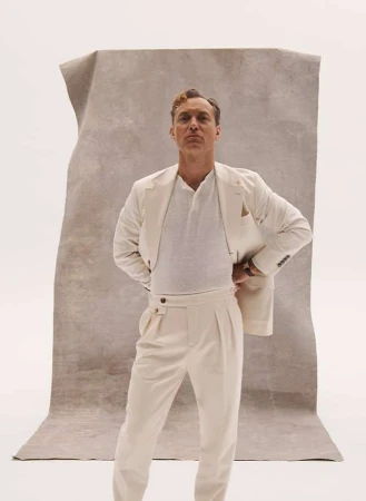 Portrait of a man in a cream-colored suit posing in front of a textured backdrop. He is fair-skinned with light brown hair.