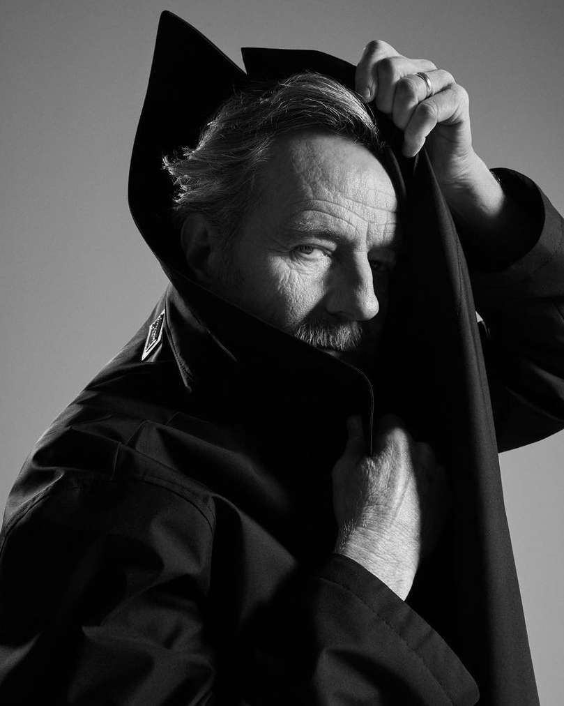 Monochrome portrait of a man with a mustache, partially obscured by a dark coat, creating a dramatic and mysterious visual aesthetic.