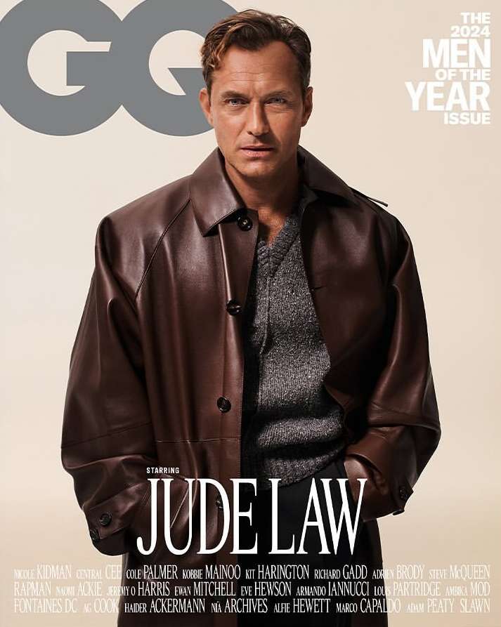 Jude Law, the 2024 Men of the Year, poses on the cover of GQ magazine wearing a brown leather jacket and grey sweater.
