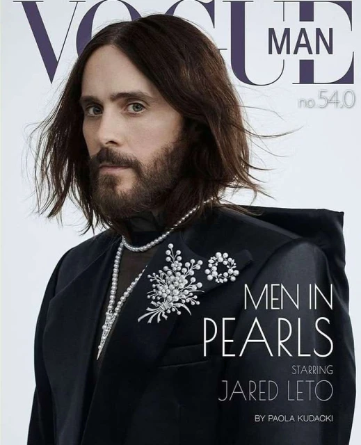 Vogue Man cover featuring Jared Leto in a black suit, pearl jewelry, and dark medium-length hair, captured in a close-up studio portrait.