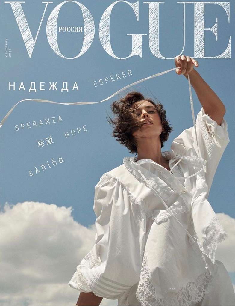 Vogue Russia cover featuring a woman in white dress holding a ribbon against a bright blue sky with scattered clouds and bold typography.