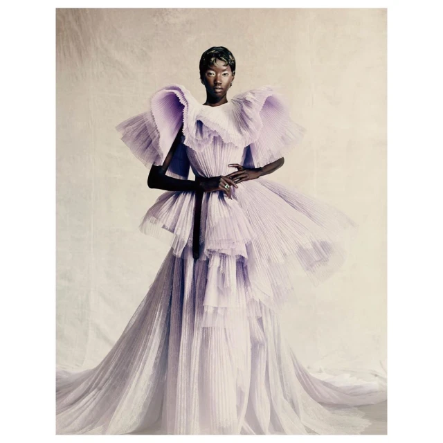Elegant Black woman in a light purple, ruffled high-fashion gown poses in a studio setting, creating a striking and sophisticated portrait.