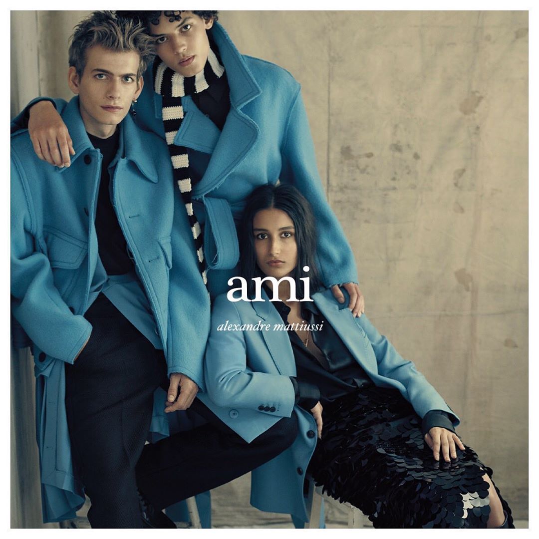 Three fashion models showcase teal coats and black attire against a neutral backdrop. Fashion-forward outerwear and chic styling.
